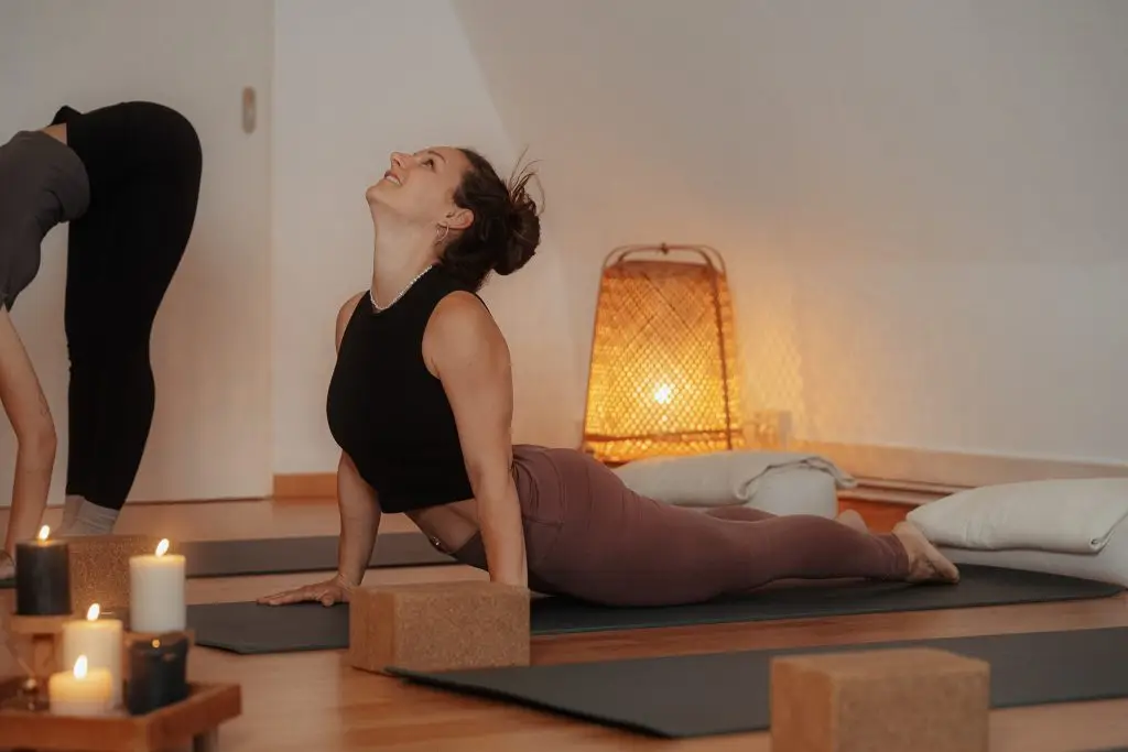 Dynamisches Vinyasa Yoga in Rostock: Yogalehrerin Julia praktiziert die Kobra-Pose (Bhujangasana) in einem fließenden Kurs im stimmungsvoll beleuchteten Studio.