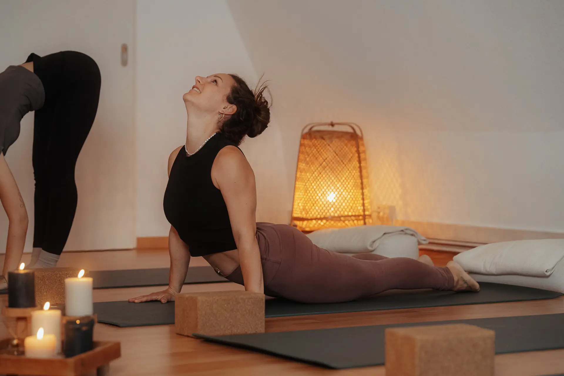 Dynamisches Vinyasa Yoga in Rostock: Yogalehrerin Julia praktiziert die Kobra-Pose (Bhujangasana) in einem fließenden Kurs im stimmungsvoll beleuchteten Studio.