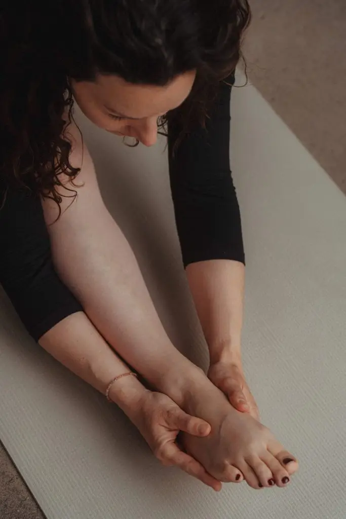 Nahaufnahme einer Yoga-Praktizierenden in einer tiefen sitzenden Vorbeuge (Paschimottanasana) bei youyoga Rostock – Fokus auf Achtsamkeit und Selbstwahrnehmung.