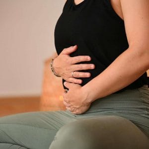 Detailaufnahme einer werdenden Mama, die ihre Hände liebevoll auf den Bauch legt, während einer Einheit der Schwangerenvideokursreihe bei youyoga Rostock.