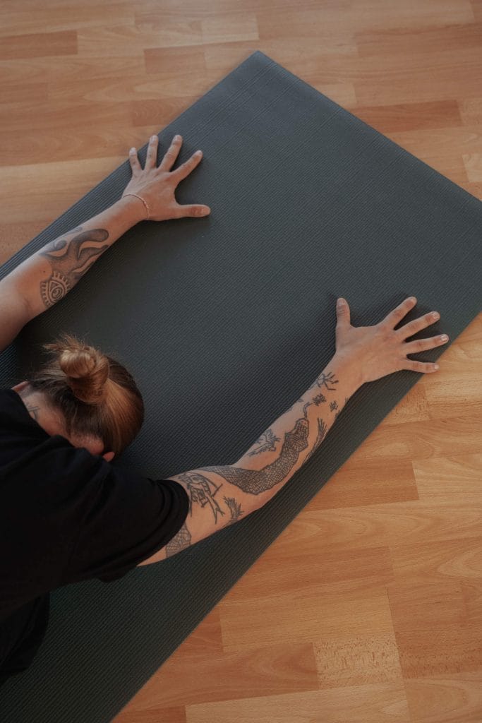 Draufsicht auf eine yoga-praktizierende Person in einer tiefen Vorbeuge auf der Matte bei youyoga Rostock – Symbol für Hingabe und Fokus.