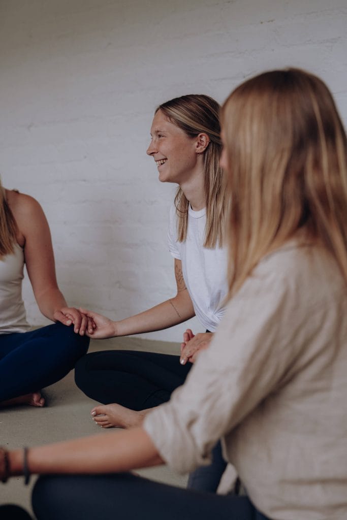 Glückliche Teilnehmerinnen in einer herzlichen Gemeinschaftsrunde bei youyoga Rostock – Erfahrungen und Testimonials aus unseren Yogakursen.