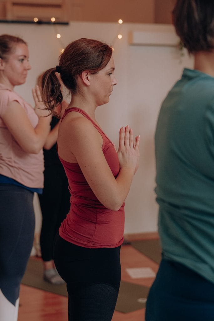 Kursteilnehmerinnen bei einer zentrierenden Übung in Gebetshaltung (Anjali Mudra) während eines Yoga-Workshops bei youyoga Rostock.
