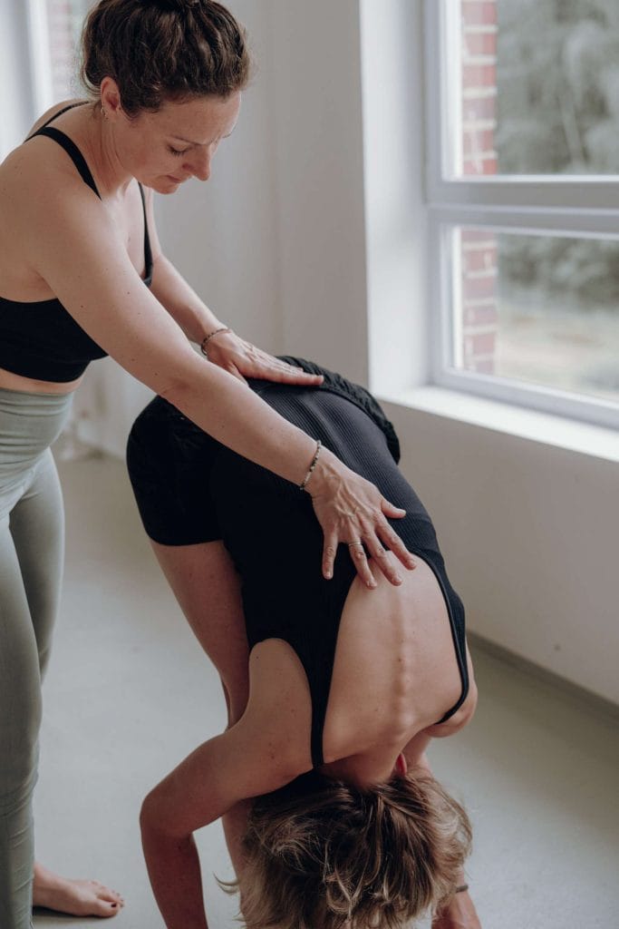 Yogalehrerin Julia gibt im Sonnengruß Tutorial bei youyoga Rostock eine präzise Hilfestellung zur Ausrichtung des Rückens in der stehenden Vorbeuge (Uttanasana).